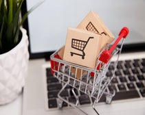 Mini shopping trolley full of boxes on laptop keyboard