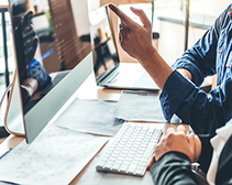 Hand pointing to computer screen Website maintenance costs UK 2022