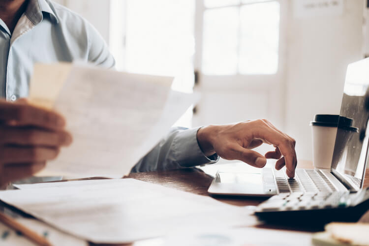 Man in buttoned shirt sorting through invoices