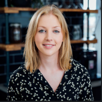 A head shot of Natasha Willett - a blonde woman in a work shirt with a blue background