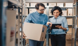 man and woman in a stockroom looking at best inventory management software on an ipad