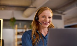 Femme souriante passant un appel depuis un micro-casque.