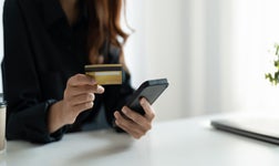 Close up of woman hold bank credit card shopping online using mobile phone, buying goods or ordering online, entering bank accounts and details in online banking offer