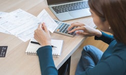 young business woman using calculator to calculate expenses of monthly, hand holding bills and receipt for to payment on desk
