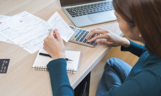 young business woman using calculator to calculate expenses of monthly, hand holding bills and receipt for to payment on desk