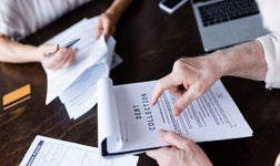 Person out of picture holding a clipboard with a document stating debt collection