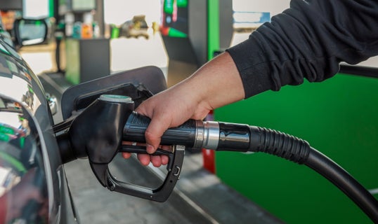 person holding pump and filling up their vehicle with gas