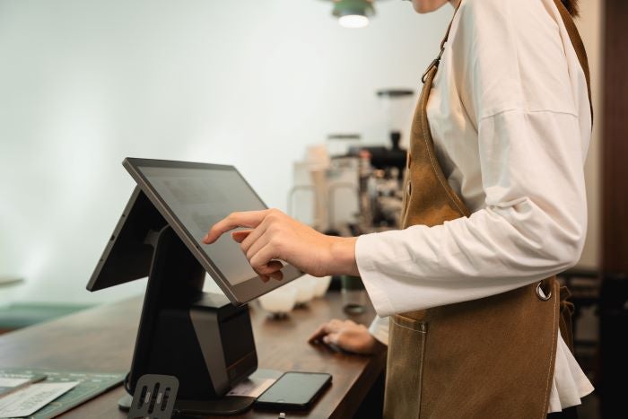 Un employé debout derrière un comptoir utilisant un logiciel de caisse enregistreuse.