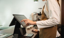 Un employé debout derrière un comptoir utilisant un logiciel de caisse enregistreuse.