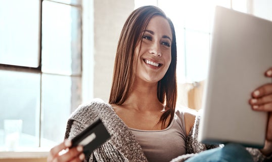 woman looking at tablet with credit or debit card in hand ready to make a payment