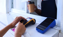 person paying on a card reader to a business merchant account at a coffee truck