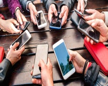 cropped shot of the hands; eight people in a circle, all holding smartphones