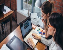 two people looking over a website design on a laptop