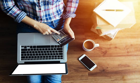 Person using calculator and laptop