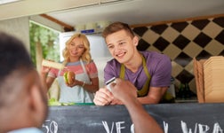 man paying for food at a hot dog food truck via POS card system