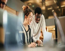 Two Creative Colleagues Using Laptop to Discuss Work Project at Office