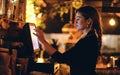 Female server using a point of sale system in an evening restaurant setting