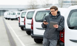 Un chef de flotte devant des camions avec un fichier et téléphone