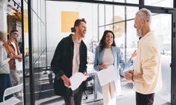 Three members of staff laughing and chatting in their work office