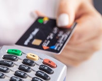 a person holding a card above a credit card machine