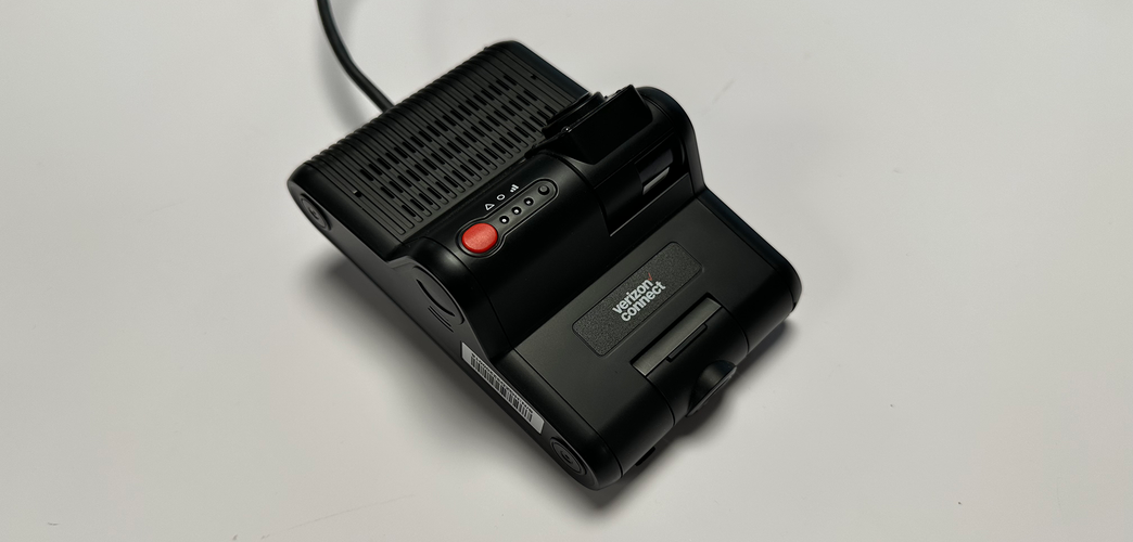 Verizon Connect Dual-Facing AI Dashcam face up showing controls, cameras and cable on an off-white background