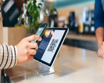 A person scans a QR code on a POS system.