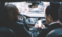 two people in car looking at GPS tracking on smartphone and on in-vehicle screen