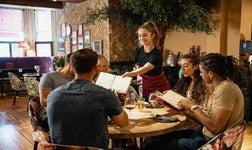 Waitress handing a table of guests menus at a restaurant