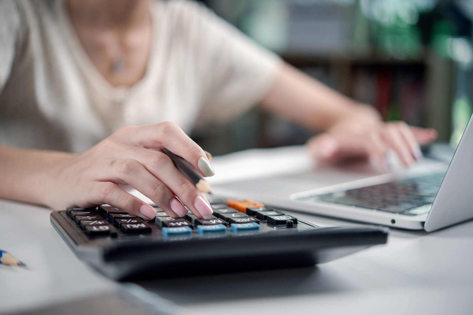 Businesswoman at desk using a calculator and laptop