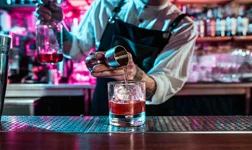Barman making cocktail on bar top using measuring cup.