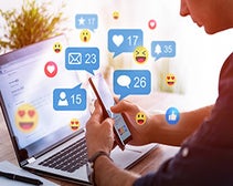 Man looking down at phone and laptop using social media marketing tools 2022