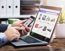 man shopping on smart phone in front of laptop ecommerce platform