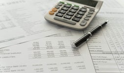 Close-up of a financial report document with a calculator and pen indicating financial analysis.