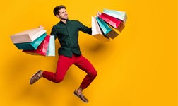 Happy man jumping up and holding colorful shopping bags
