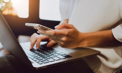 holding mobile phone over laptop