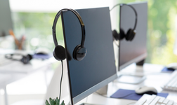 headsets hanging on monitor screens used for VoIP cloud phone calls