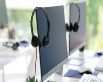 headsets hanging on monitor screens used for VoIP cloud phone calls