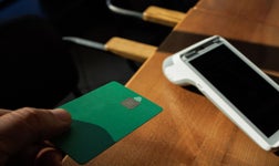 A man accepts payment from a customer through a credit card terminal in a store or cafe.