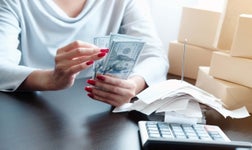 woman counting money beside calculator