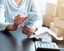 woman counting money beside calculator
