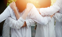 back view of young people linking arms