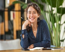 woman wearing glasses holding a pen smiling