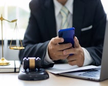 lawyer in the office using a cell phone beside golden scales