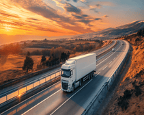 A lorry on a highway in front of an orange sunset.