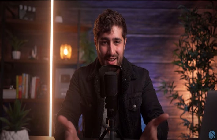 still from Create a Pro website video showing a speaker in front of a microphone at a desk