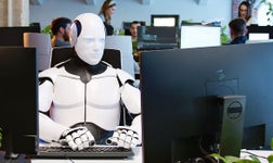 futuristic robot typing at a computer in an office