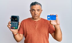 sad man holding a card and a card machine