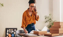 woman on the phone in her office surrounded by boxes to unpack and set up office