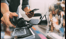 A person puts down a VoIP headset to configure something on their mobile device.