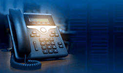 A VoIP-compatible desk phone sitting on a desk.